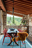 Essbereich auf überdachter Terrasse mit Steinmauern und Holzbalkendecke