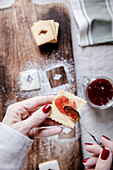 Spreading Linzer biscuits with red berry jam