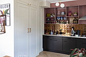 Kitchen unit with golden tiled backsplash and open, pink shelves