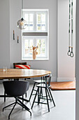 Round wooden table with black chairs in modern dining room with gymnastic rings