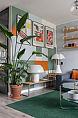 Living room with modern art prints, green carpet and tall houseplant in terracotta pot