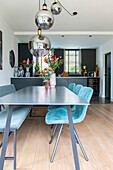 Dining room with light blue upholstered chairs and metal pendant lights