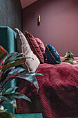 Bedroom with burgundy textiles and green headboard