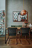 Dining area with copper-coloured pendant light and upholstered chairs in front of grey wall with photo art