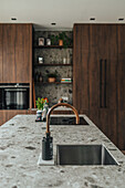 Modern kitchen with natural stone worktop and copper mixer tap