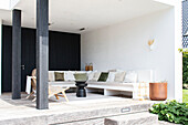 Modern covered terrace with lounge seating area and white and green cushions