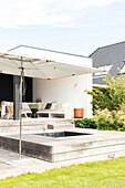 Modern terrace with sunken hot tub and parasol in the garden