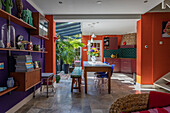 Open kitchen with dining area with colourful walls and glass roof