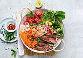 Rice noodle and vegetable bowl with grilled steak