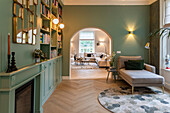 Living area with green wall colour, bookshelf and arched opening to the living room