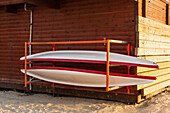 Red and white canoes on rack at shed\n