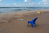 Plastic chairs on wet sandy ocean beach, Bat Yam, Israel\n