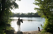 Girl on horseback with dogs wading in idyllic summer lake, Dolgen am See, Mecklenburg, Germany\n