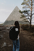 Female hiker with backpack looking at stone pyramid, Balmoral, Cairngorms, Scotland\n
