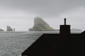 Felsformationen jenseits des Daches über dem Meer, Bour, Vagar, Färöer Inseln