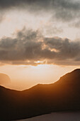 Sonnenuntergang in Wolken über dem Meer und silhouettierten Klippen, Klakkur, Klaksvik, Färöer Inseln