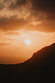 Sonnenuntergang im orangen Himmel über silhouettierten Klippen und Meer, Klakkur, Klaksvik, Färöer Inseln