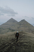 Man hiking on grassy hill, Klakkur, Klaksvik, Faroe Islands\n