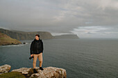 Hiker with camera at the edge of cliff over ocean, Neist Point, Isle of Skye, Scotland\n