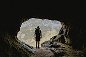 Männlicher Wanderer steht am Eingang einer schroffen Berghöhle, Assynt, Sutherland, Schottland