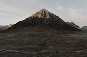 Sonnenlicht über einem zerklüfteten, majestätischen Berggipfel bei Sonnenaufgang, Glencoe, Schottische Highlands, Schottland