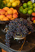 Still life fresh grapes, nectarines and citrus fruits in bowls\n