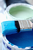 Close up of blue paint pot and paintbrush\n