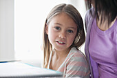 Young girl sitting on mother lap smiling\n