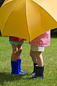 Two young girls under yellow umbrella\n
