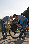Zwei Frauen prüfen Fahrradreifen auf der Landstraße