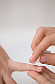 Close up of manicurist's hand cleaning woman's finger with cleaning pad\n
