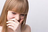 Young woman laughing with hand in front of mouth\n