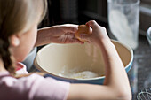 Close up of young girl breaking eggs\n