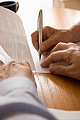 Close up of man and woman hands signing documents\n