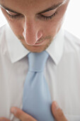 Close up  of a young man straightening his tie\n