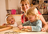 Portrait of young blonde woman with little girls smiling and baking\n