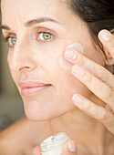 Close up of woman applying moisturizing cream\n