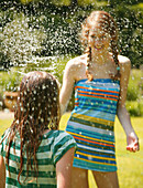 Portrait eines Teenagers, der ein Mädchen mit Wasser besprüht