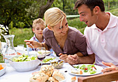 Couple and young boy having lunch outside\n