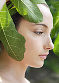 Portrait of a young woman with green fig leaves\n