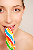 Junge Frau lächelt und isst einen bunten Eislutscher