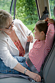 Grandmother adjusting seatbelt for granddaughter\n