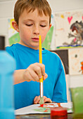 Porträt eines Jungen beim Malen mit Wasserfarben