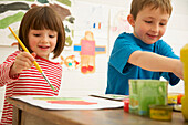 Portrait of young boy and young girl painting and smiling\n