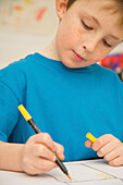 Portrait of young boy coloring with pen\n