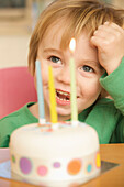 Toddler and birthday cake with three candles\n