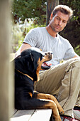 Man sitting under porch with his dog\n