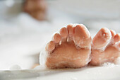 Close up of woman feet covered in foam coming out of bathtub\n