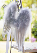 Close up of white feather wings hanging from  garden chair\n
