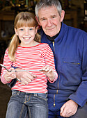 Portrait of grandfather and granddaughter holding wrenches smiling\n